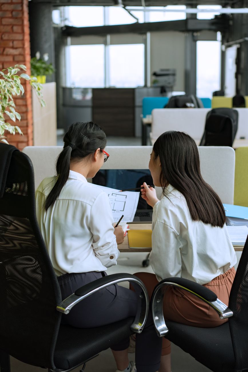 Two colleagues reviewing work together in a bright open-plan office