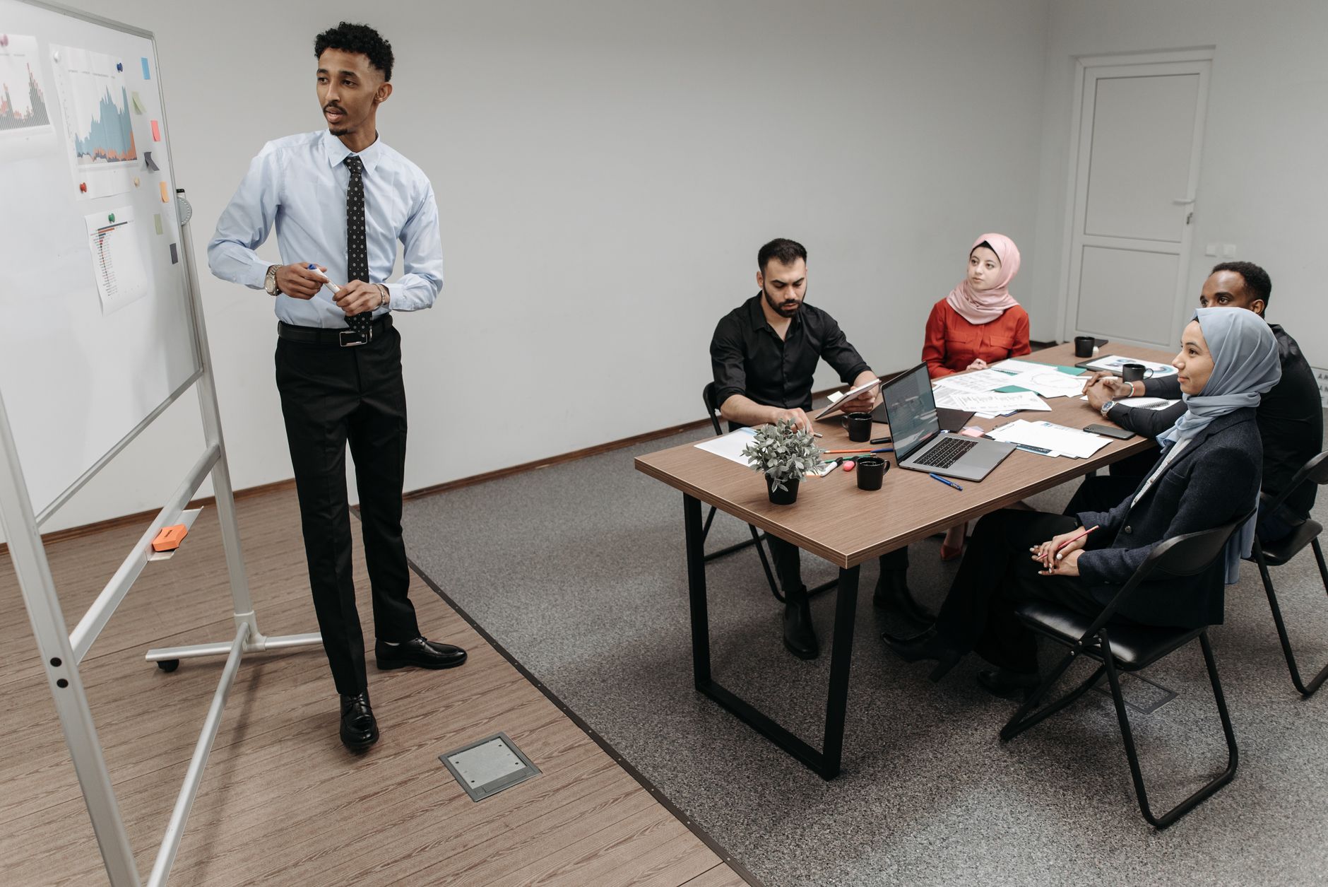 A manager presenting to a diverse team around a meeting table